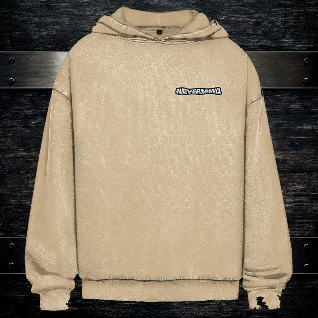 Beżowa bluza z kapturem typu boxy fit z logo NEVERMIND na piersi, tło ciemne drewno i grafitowy metal.