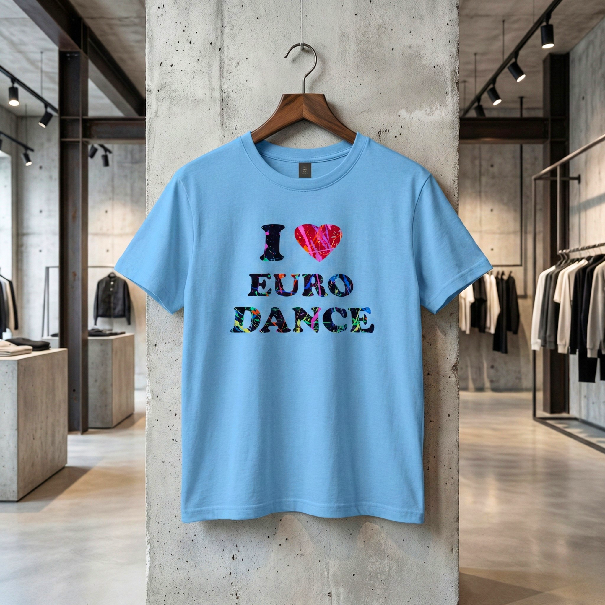 Jasnoniebieska koszulka z kolorowym, graffiti napisem "I ❤️ EURO DANCE" wisząca na drewnianym wieszaku w nowoczesnym, industrialnym sklepie odzieżowym z betonowymi ścianami.